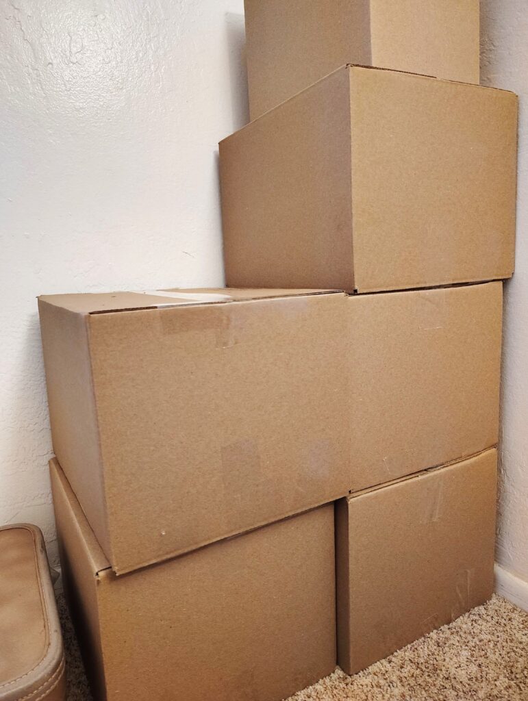 a stack of cardboard moving boxes stacked in the corner of a room